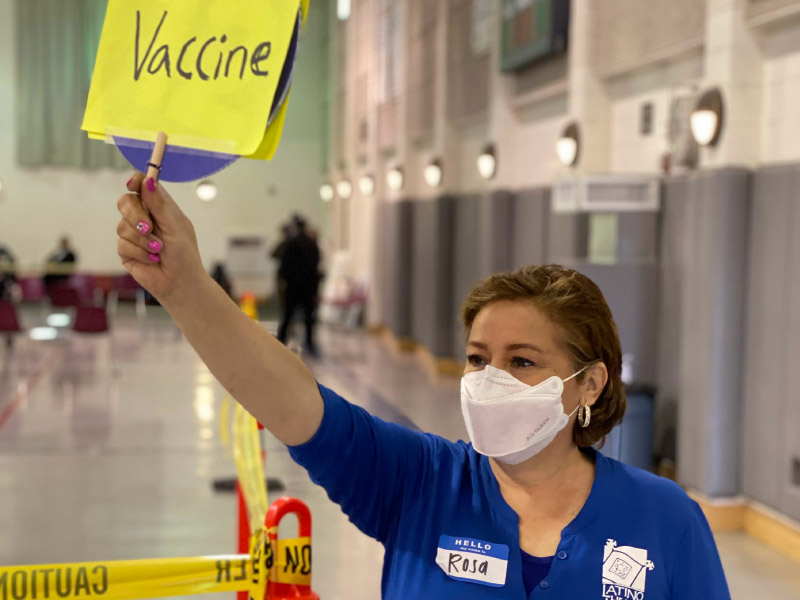 在加州圣安娜的维拉中级学校，拉美裔健康促进者罗莎·卡尔德隆帮助登记接种疫苗的人进行分类。(图片由拉丁美洲健康通道提供)