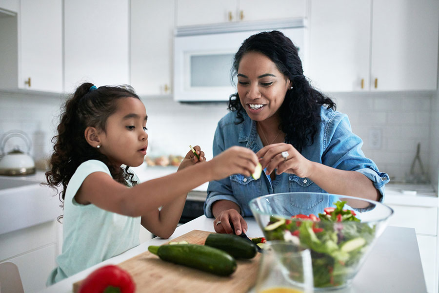 Mom and daughter make salad in kitchen