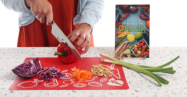 美国心脏协会烹饪彩色食谱，在切菜板上切菜的手特写