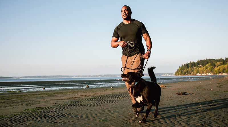 男子带着宠物狗在海滩上奔跑