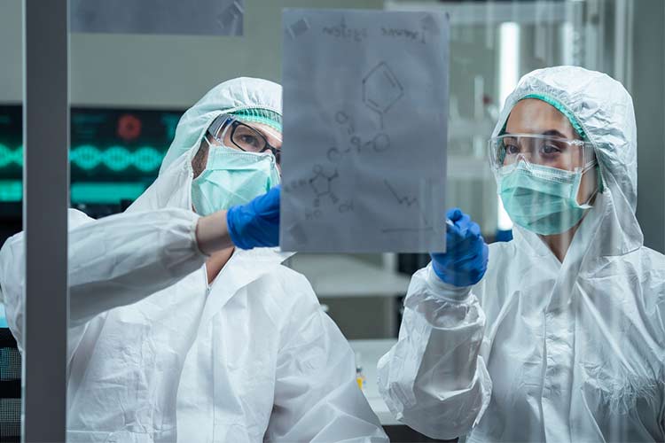 两名实验室工作人员戴着个人防护装备分析冠状病毒结构。