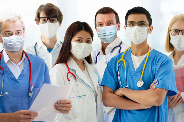 几名戴着口罩的医护人员站在一起，面对镜头。